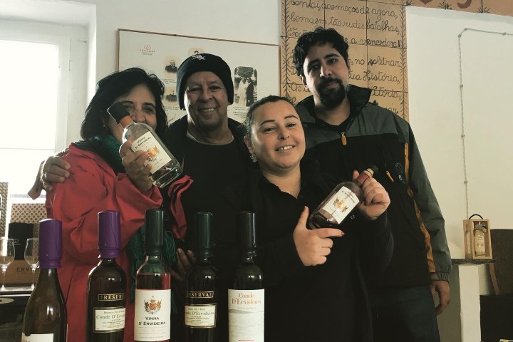 a group of people standing next to a bottle of wine